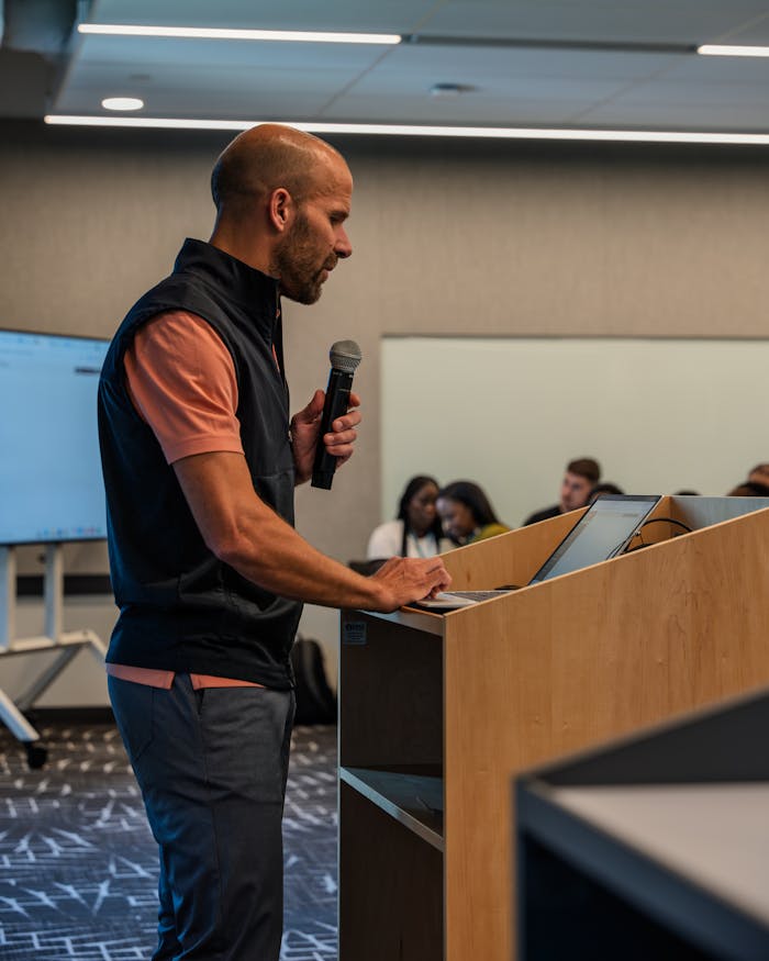 Professional presenting with microphone during a business meeting in a conference room.
