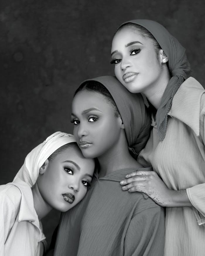 Black and white portrait of three Nigerian women in traditional attire, conveying elegance and unity.